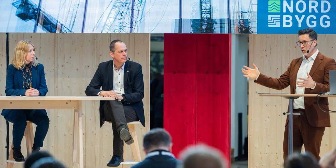 Paneldiskussion med branschexperter vid ett bord på scen under Nordbygg, som belyser framtidens byggfrågor